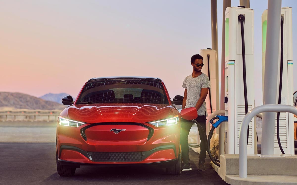 A man plugs in a Mustang Mach-E at a public charging station